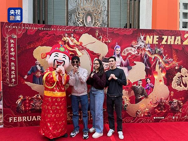 △当地时间2025年2月8日，《哪吒之魔童闹海》（NeZha2）洛杉矶首映礼上，观众在电影海报前合影。
