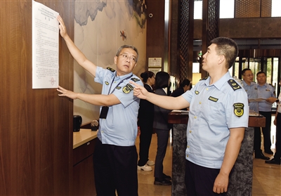 图为市场监管部门工作人员在酒店醒目处张贴价格监管措施公告。于宏 摄