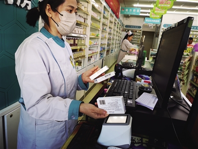 药店销售人员展示药品追溯码 高燕 摄