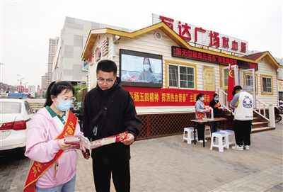 图为志愿者向过往市民宣传无偿献血知识。　韩堃摄