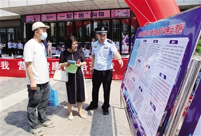 图为7月18日，公安民警通过展板向市民宣传打击整治网络谣言专项行动的典型案例。韩堃摄