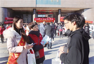 图为工作人员向大学生发放宣传资料。韩堃摄