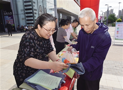 图为现场工作人员发放宣传资料、宣传老年健康知识。戎禹仁摄