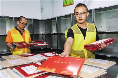 图为邮件快递处理中心工作人员正在整理新到的高考录取通知书。韩堃摄