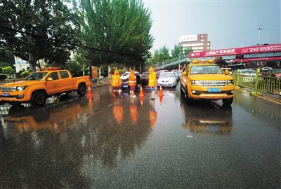 图为，环卫部门对积水路段采取道路封控导行措施，以确保市民出行安全。高雅敏摄