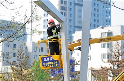 图为专业人员在太和路梳理捆扎路灯杆上缠绕的电线。于宏摄