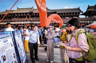 图为民辅警通过展板向市民进行反诈宣传。韩堃摄