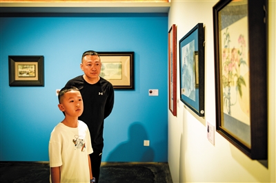 图为一对父子沉浸在经典绘画特展的艺术氛围中。韩堃摄