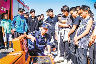 图为消防人员向市体校学生展示消防救援器材。韩堃摄