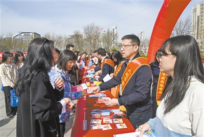 图为在活动现场，工作人员通过悬挂宣传横幅、发放宣传资料、现场讲解等方式为大家答疑解惑。张燕伟摄