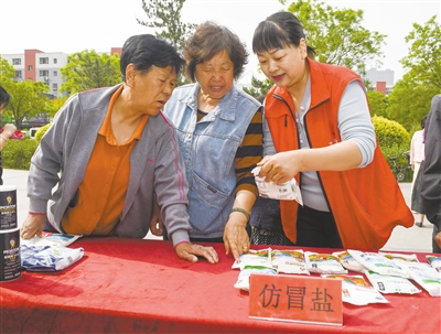 图为工作人员向市民普及识别劣质食盐的方法。戎禹仁摄