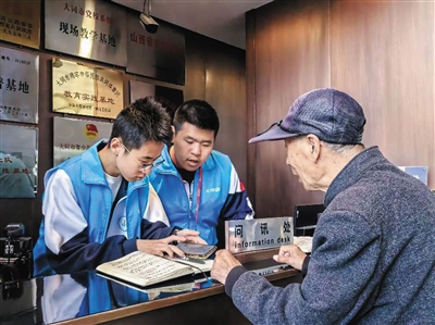 图为青年志愿者帮游客查询出行路线。韩堃摄