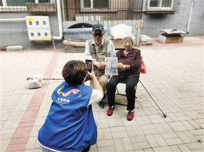 图为社区网格员为高龄老人提供照片采集服务。孙露摄