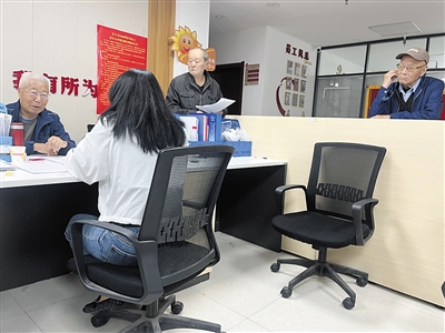 图为，社区工作人员为老年人宣传政策，办理各项业务。资料图片