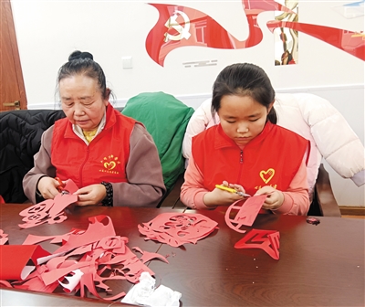 图为志愿者在裁剪窗花。锦秀摄