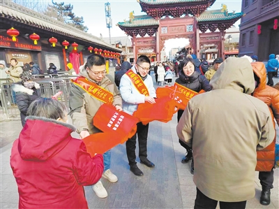 图为志愿者在古城内发放环保手提袋。图片由市政府办公室提供