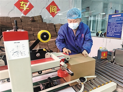 图为工作人员正在对产品装箱封口。苑捷摄