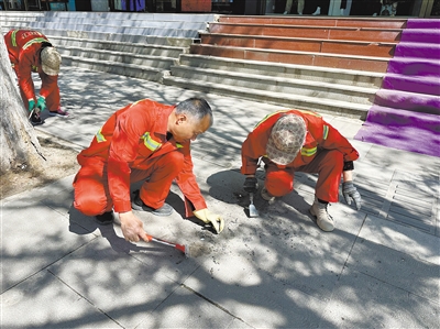 图为环卫工人清理路面口香糖残留物。杨昱郁摄
