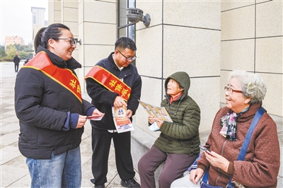 图为社保工作人员向居民发放宣传折页、解读相关政策。韩堃摄