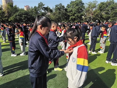 老队员为新队员佩戴鲜艳的红领巾。图片由平城区文慧小学提供