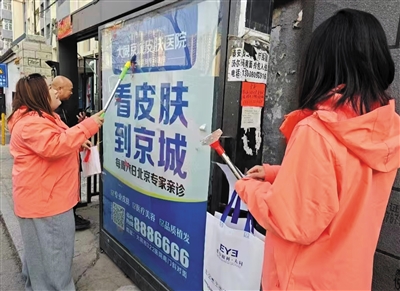 永泰街道光熙苑社区志愿者清理小区野广告。段雨萌摄
