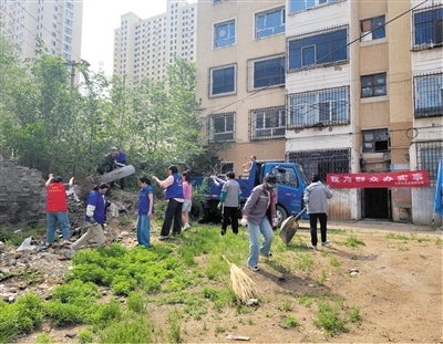社区工作人员与党员、志愿者一起清理杂物垃圾。段雨萌摄