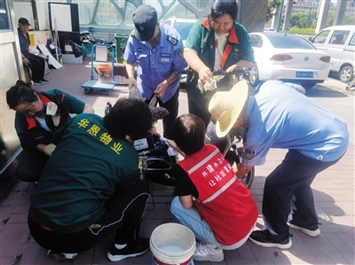 民安社区工作人员为居民清洗电动车。段雨萌摄