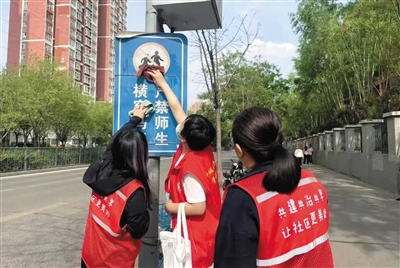 和泰社区组织志愿者清洁维护交通标识与公益宣传牌。段雨萌摄