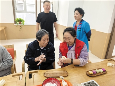 工作人员指导老人制作月饼。郑林摄