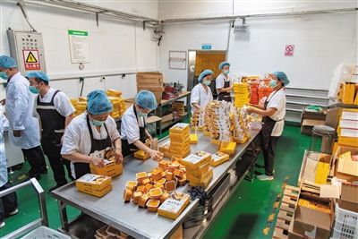 位于云冈区西韩岭乡太善村的山西思源达食品有限公司杂粮加工厂生产车间内，工人们正在将刚出笼的黄米凉糕进行分切、封装。申力摄