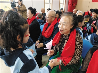 孩子们为老人佩戴红围脖。段雨萌摄