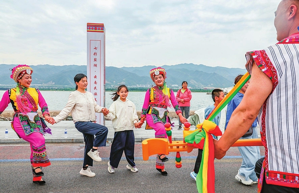 5月1日,在盐湖景区,来自云南彝族的演员身着盛装和游客们载歌载舞欢度假期。金玉敏摄