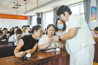 图为参训学员专注练习钩针编织技艺,授课老师手把手教学。于宏摄