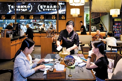 服务员将配料下入什锦火锅中。韩堃摄
